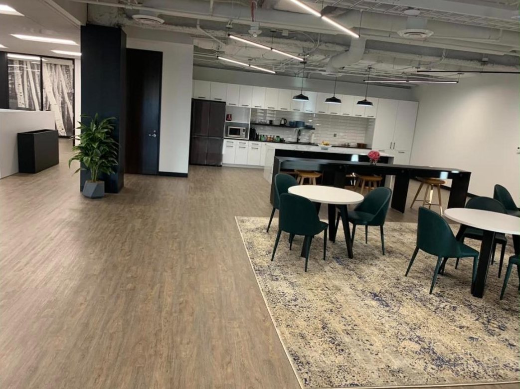 Open office cafe with white cabinetry, pendant lights and green upholstered chairs