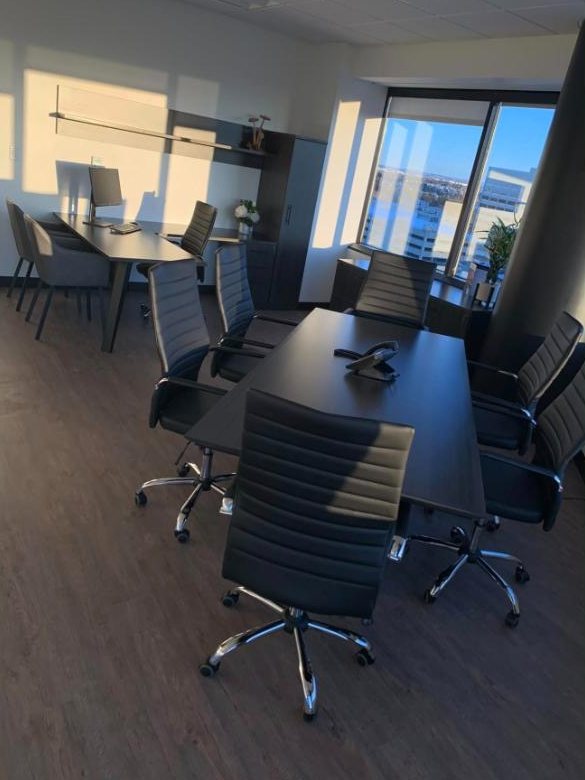Conference table with black leather chairs beside floor-to-ceiling windows