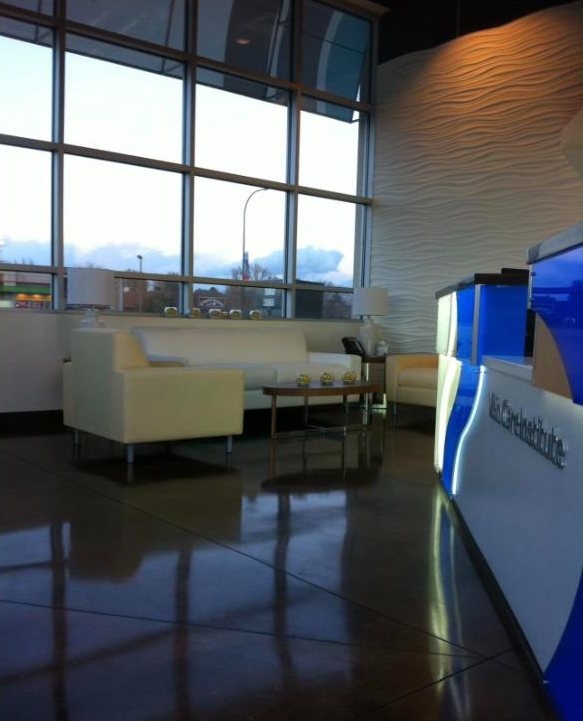 Clinic waiting area with white seating, sculpted wall and polished concrete floor