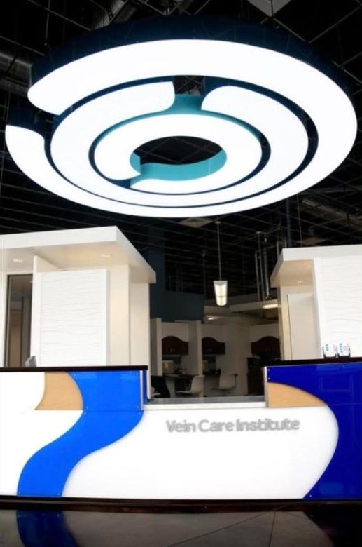 Clinic reception desk in white and blue under a large circular light fixture